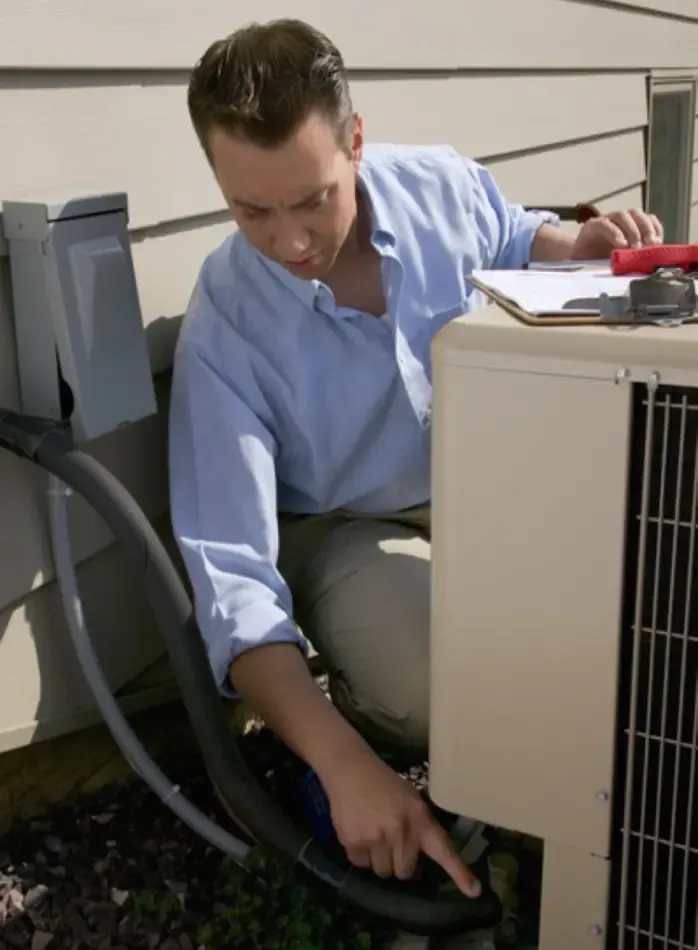 Technician inspecting an air conditioning unit outside a house.