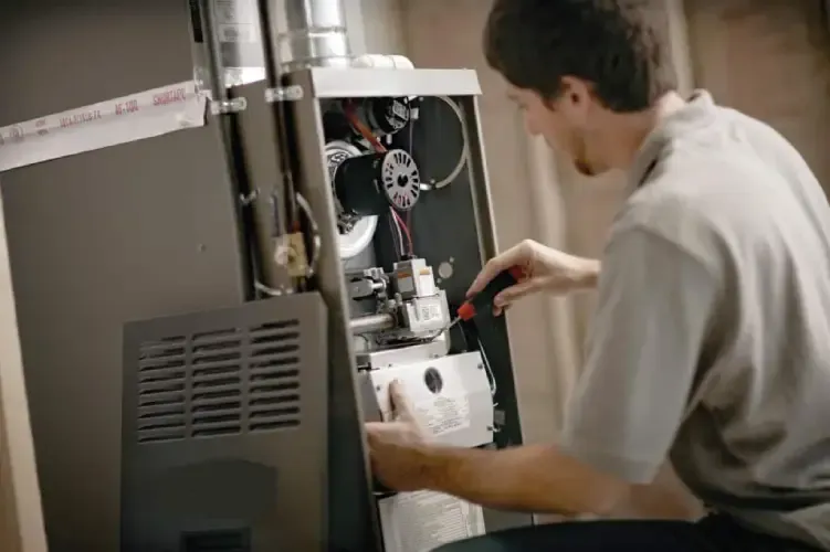 HVAC technician performing maintenance on a furnace in a residential setting
