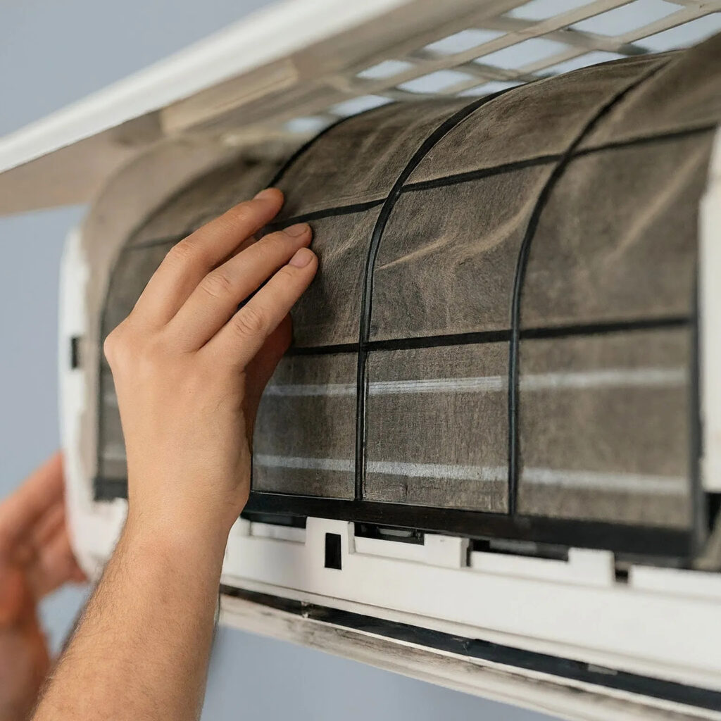 53793735-4224-447b-9e4c-3f4ace291768.webp Hand removing a dusty, clogged air conditioner filter for cleaning.